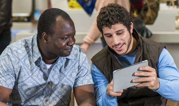 Two male students looking at tablet device together