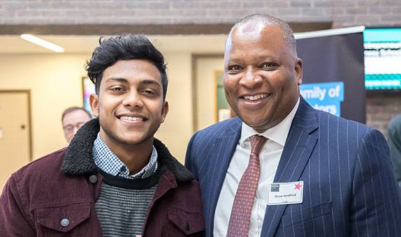 A student stands with a visitor smiling in Kingston Business School atrium